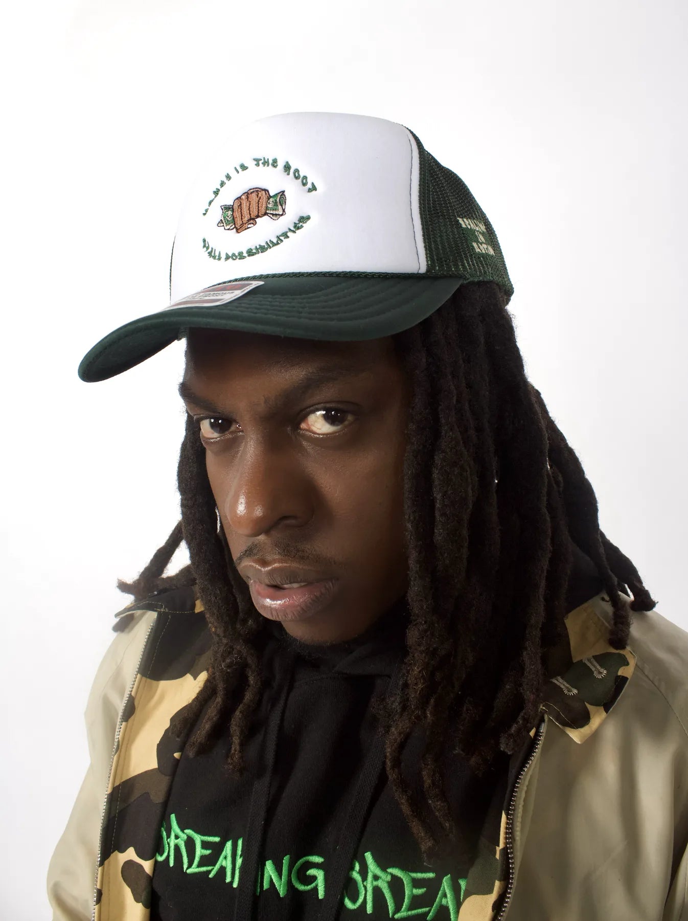 Model wearing the green and white Money Is the Root of All Possibilities hat
